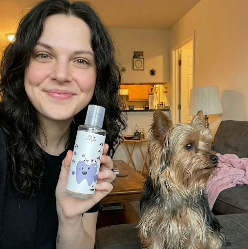 Woman holding PawBright Dental Plus with a dog sitting next to her in a home setting